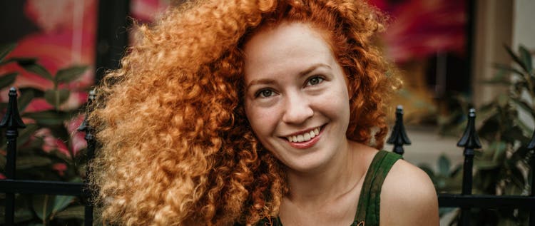 Young woman with red hair sitting outside.