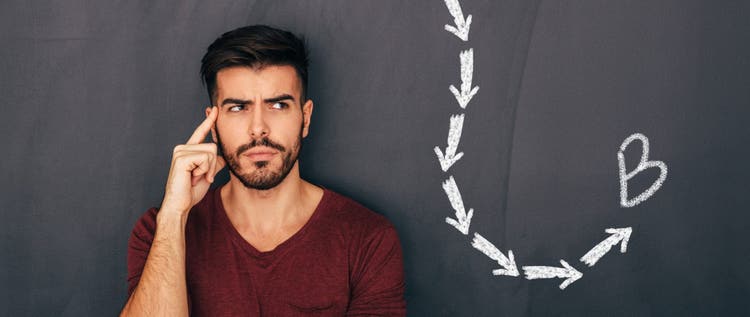 Man thinking hard in front of chalkboard showing dotted line ending at point B
