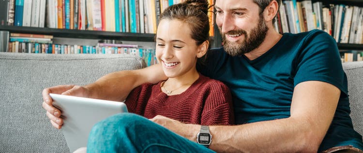father and daughter having fun with digital tablet on couch