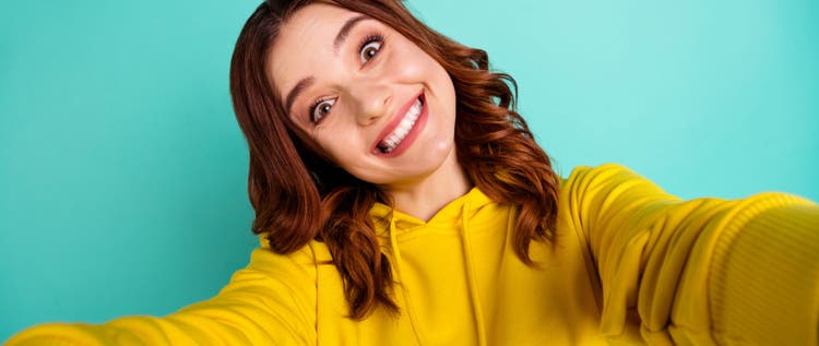 Photo of trendy cute cheerful nice millennial smiling toothily showing teeth with face expression, of joyfulness while taking selfie isolated over teal vivid color background