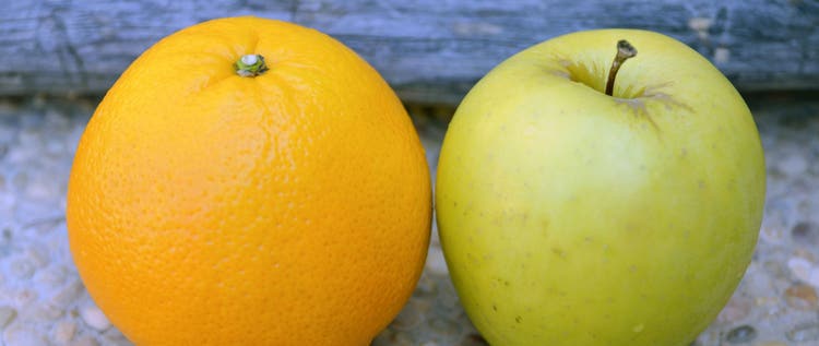 Apple and orange on wooden background close up.