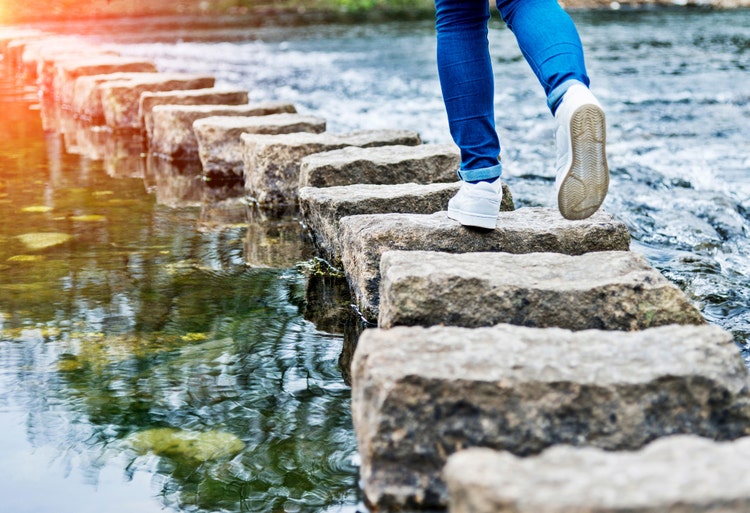 Woman crossing stepping stones on a river