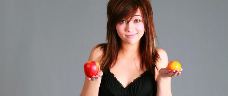 Woman holding an apple and an orange.