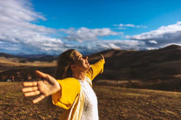 Happy woman on the sunset in nature in autumn with open hands. Young woman with eyes closed. Stress free concept.