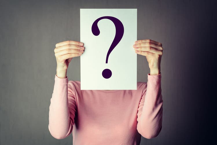 portrait of casual anonymous woman covering face with paper showing question mark.
