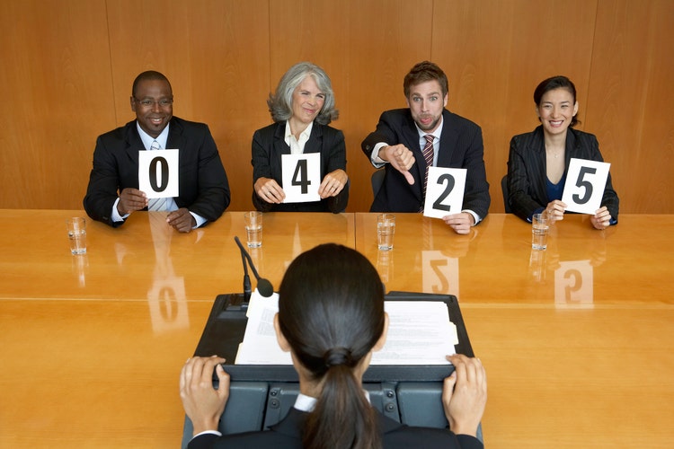 Businesswoman at interview, executives holding score cards, jeering