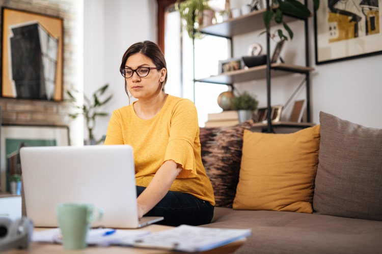 Due to lockdown and quarantine orders, woman working from home and having online meetings with colleagues. Woman is in late 30s working from authentic living room.