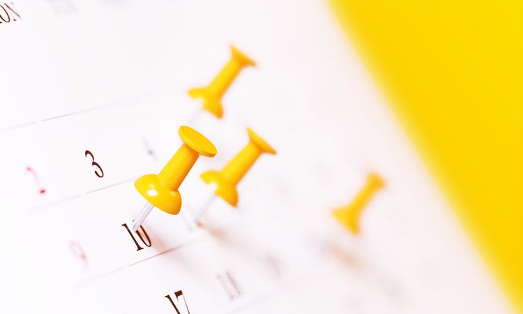 Yellow thumbtacks and white calendar before yellow background. Horizontal composition with copy space. Calendar and reminder concept.