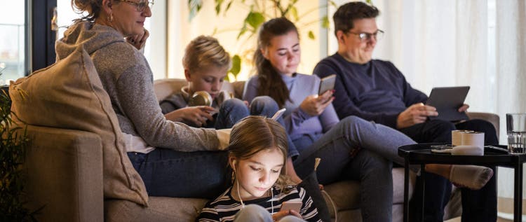 Parents sitting with children while using wireless technologies in living room at modern home