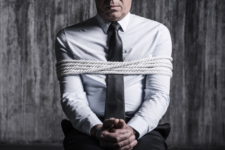 Cropped image of tied up businessman sitting at the chair with dirty wall in the background