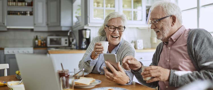 Close up of a senior couple using a phone and having breakfast
