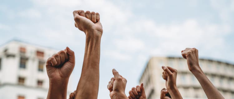 People with raised fists at a demonstration in the city. Multi-ethnic group of people together on strike.