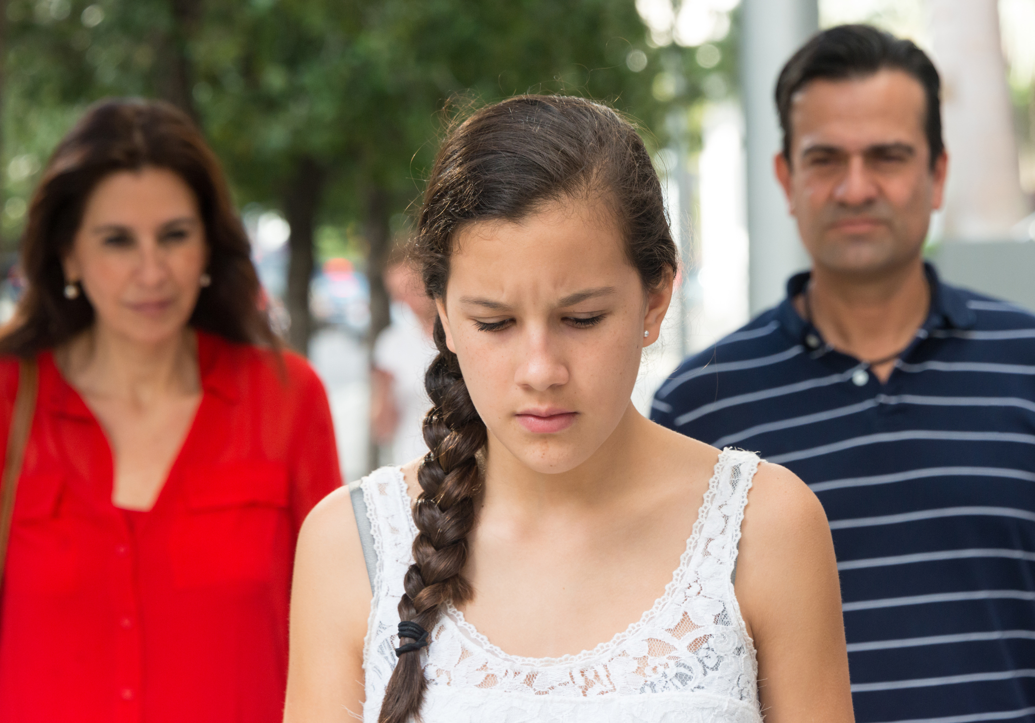 Serious Teenage girl posing with her parents in the background