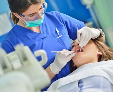 happy female dentist checking patient girl teeth up at dental clinic office