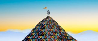 A man standing on top of a dark mountain shape made up of Google logos.