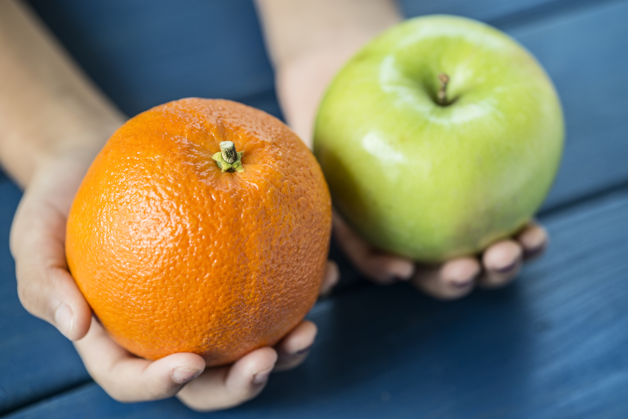 Child comparing apple to orange exhibiting the idea of comparing two completely different things