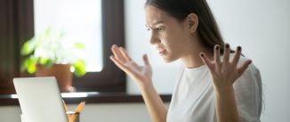 Millennial generation young adult woman looking in laptop computer, fling arms up. e.