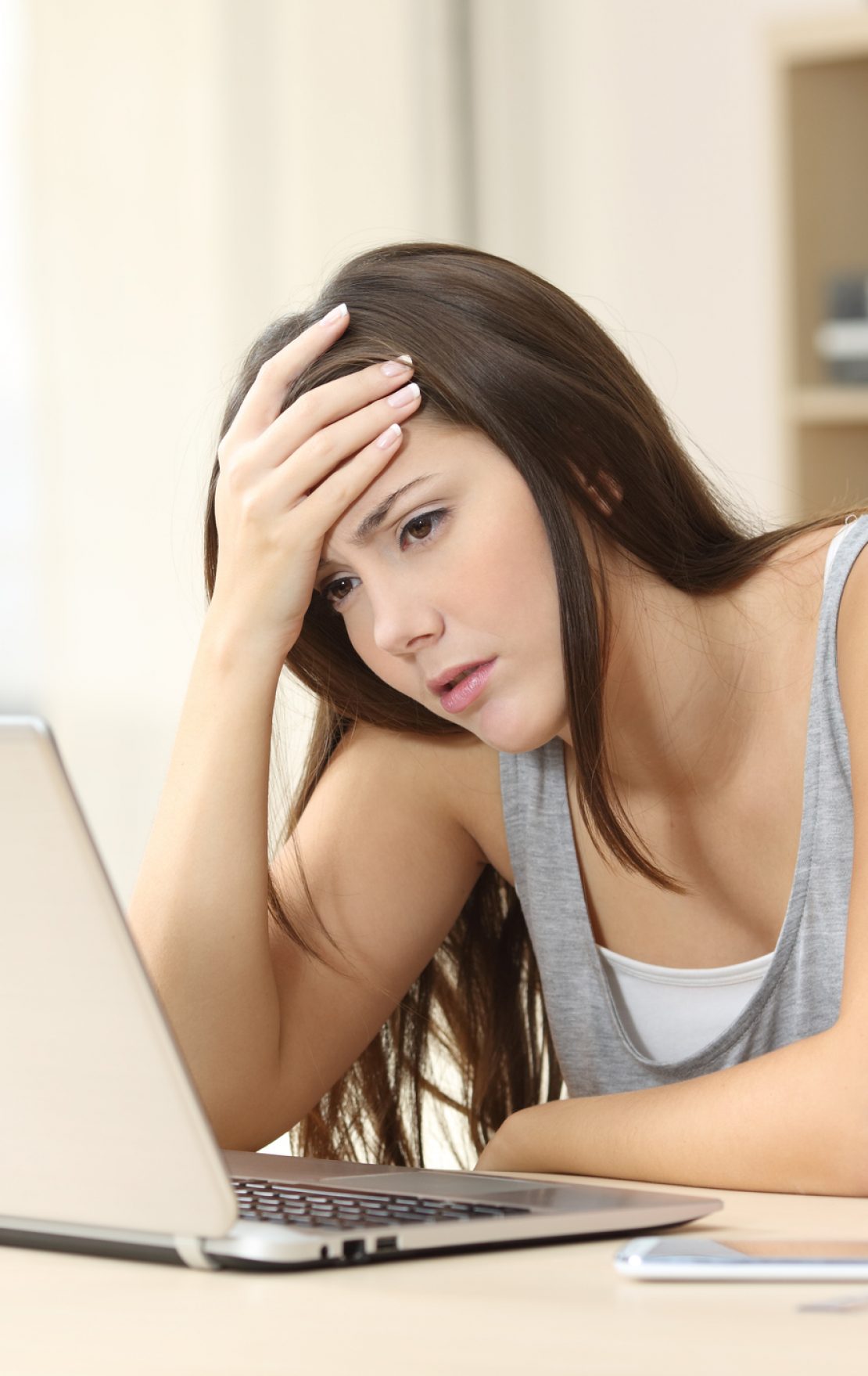 Worried and sad student female searching information in a laptop on line in a desk at home room