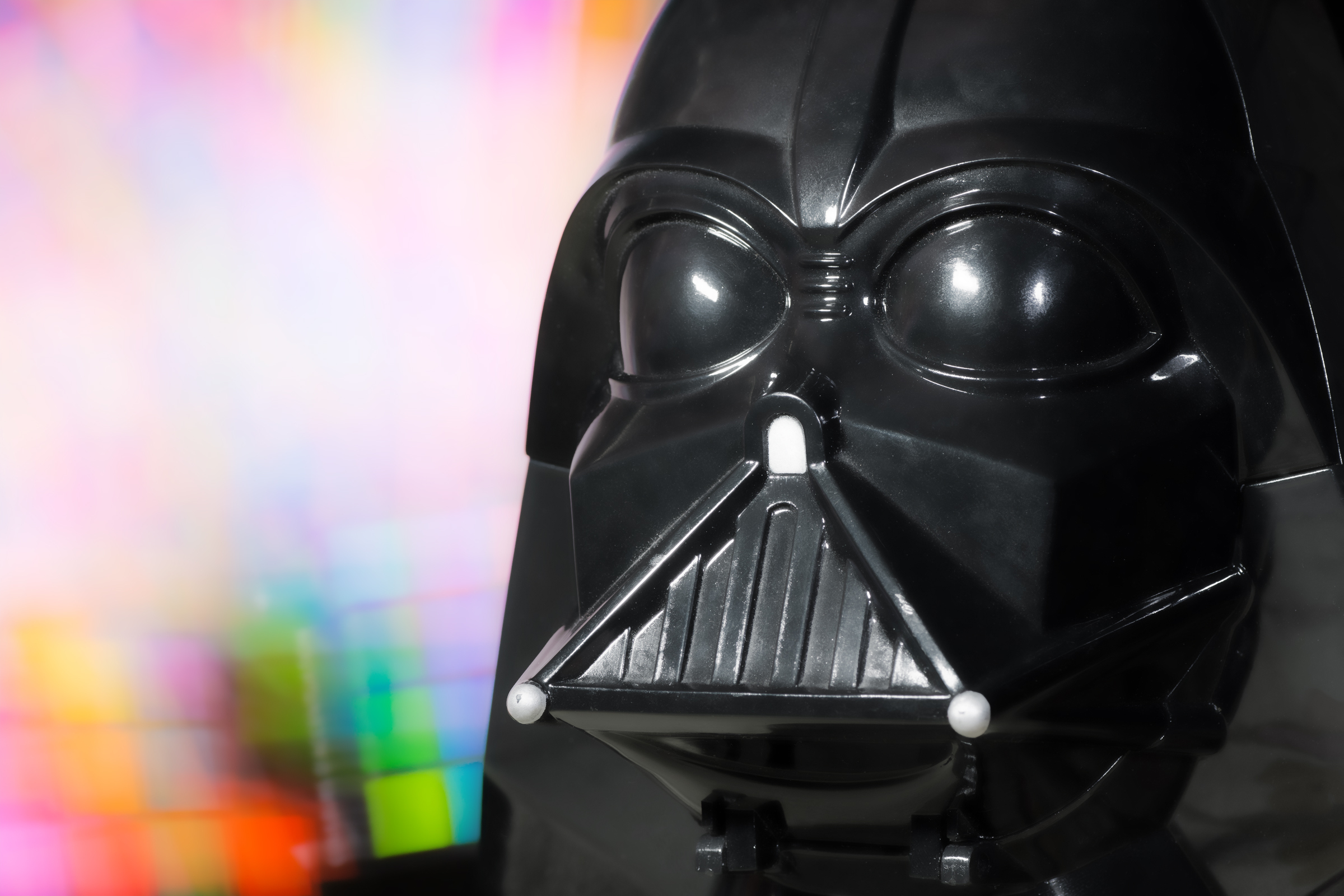 Head portrait mask costume of Darth Vader character, represents the Dark Side of the force, and he is the Luke Skywalker's father. Head portrait of Darth Vader which has been shot on colored light painting background. He is a fictional main character personnage, from the Star Wars saga films created by George Lucas in 1977 (LucasFilm ldt).