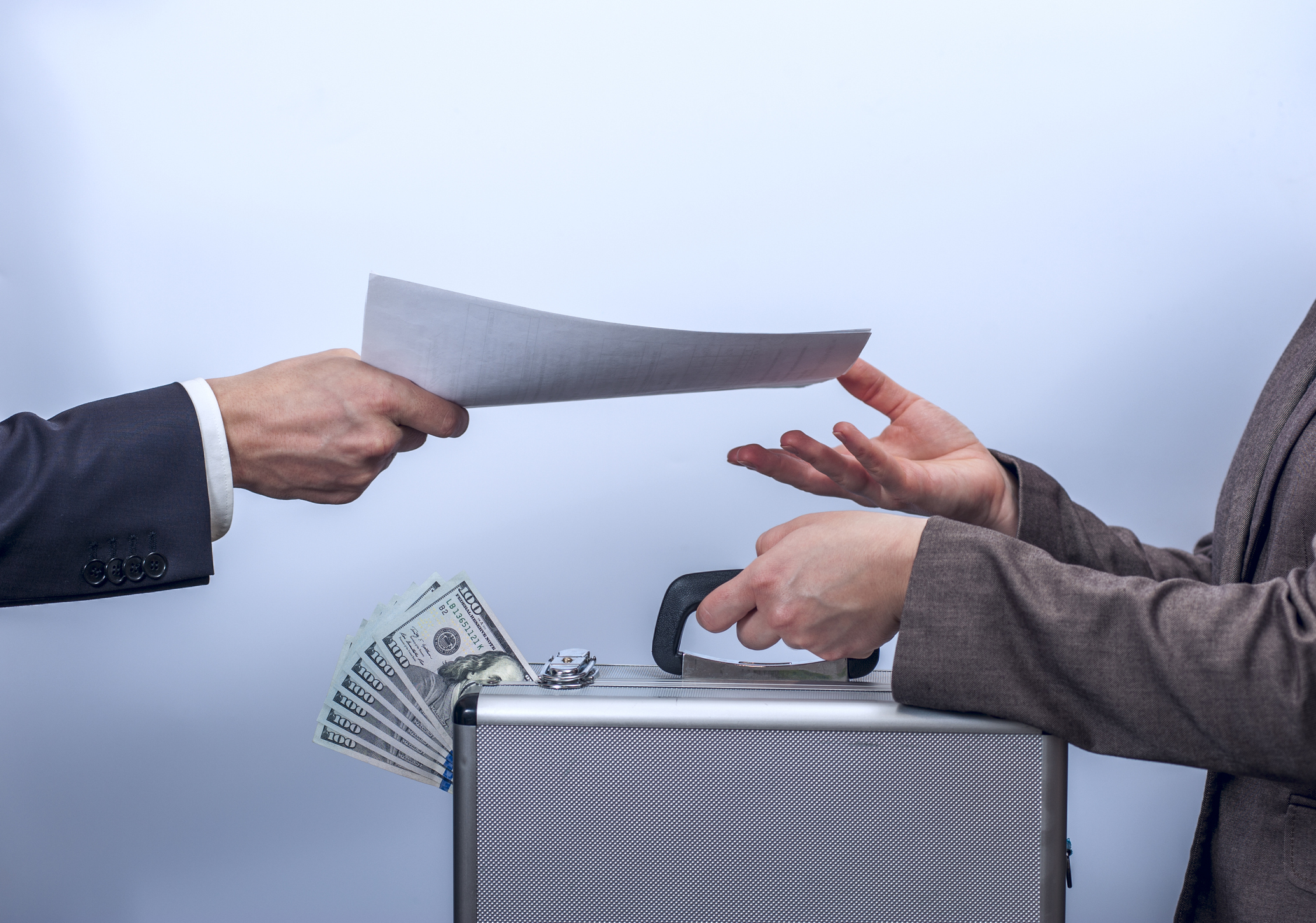 Woman in suit gives metal briefcase with dollars, man gives her important documents. Conception of safe storage and protection of cash, the exchange process. Financial theme. Horizontal view.