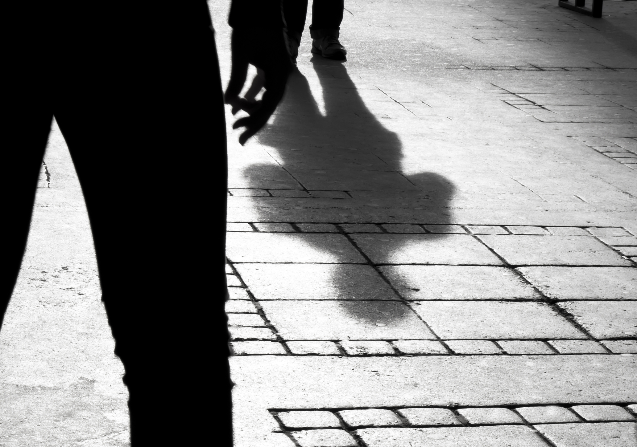 Shadow silhouette of two person on city sidewalk in black and white