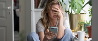 Shy Woman Using Mobile Phone At Home