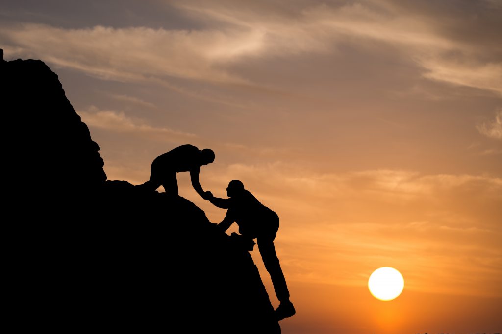 Silhouette of helping hand between two climber