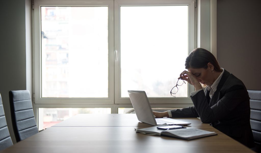 Businesswoman sitting in a office worried about a problem on her laptop, tired and under the stress