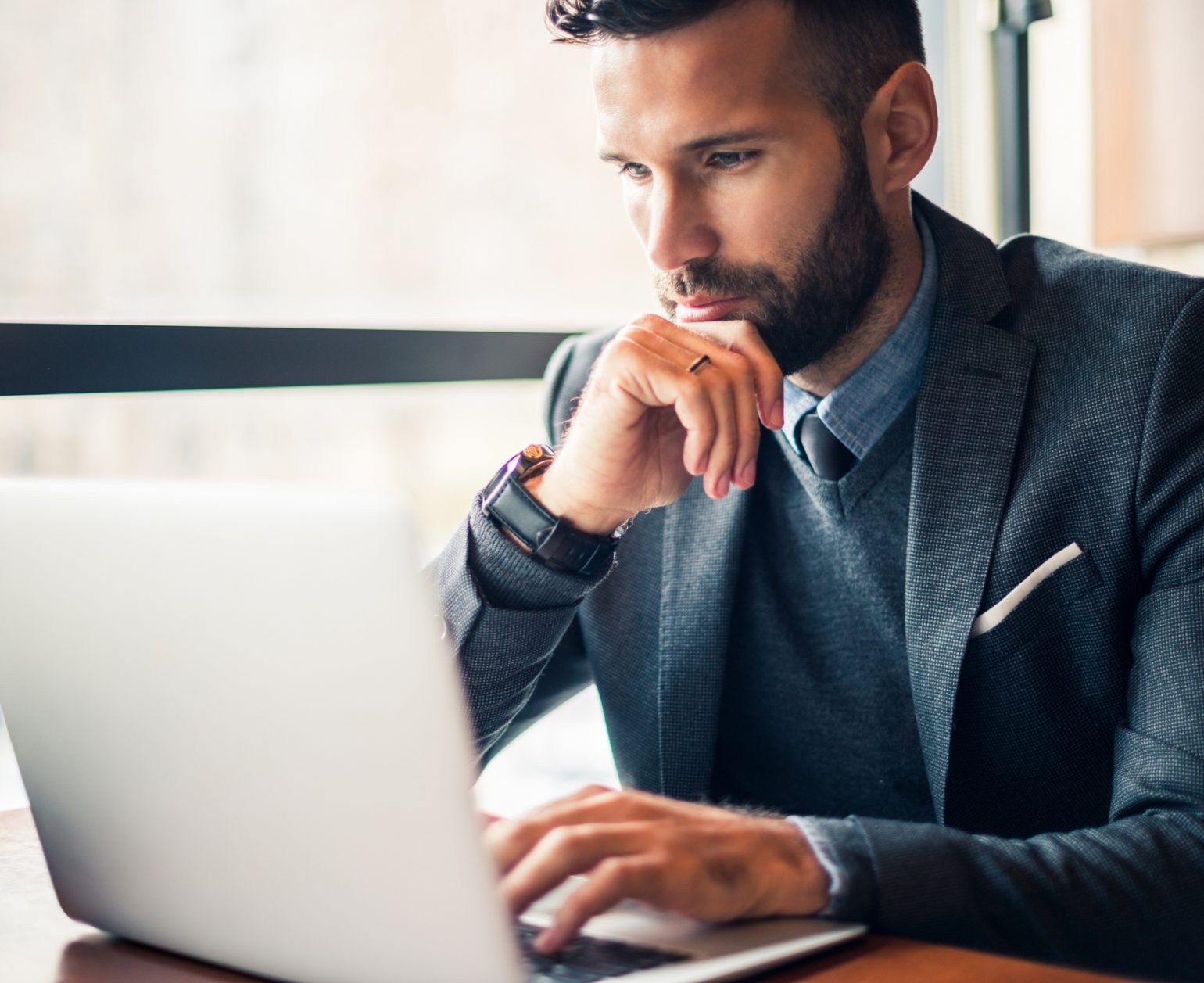 Handsome businessman working on a laptop in a cafe.