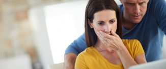 Cropped shot of a mature couple looking shocked while using a laptop together at home