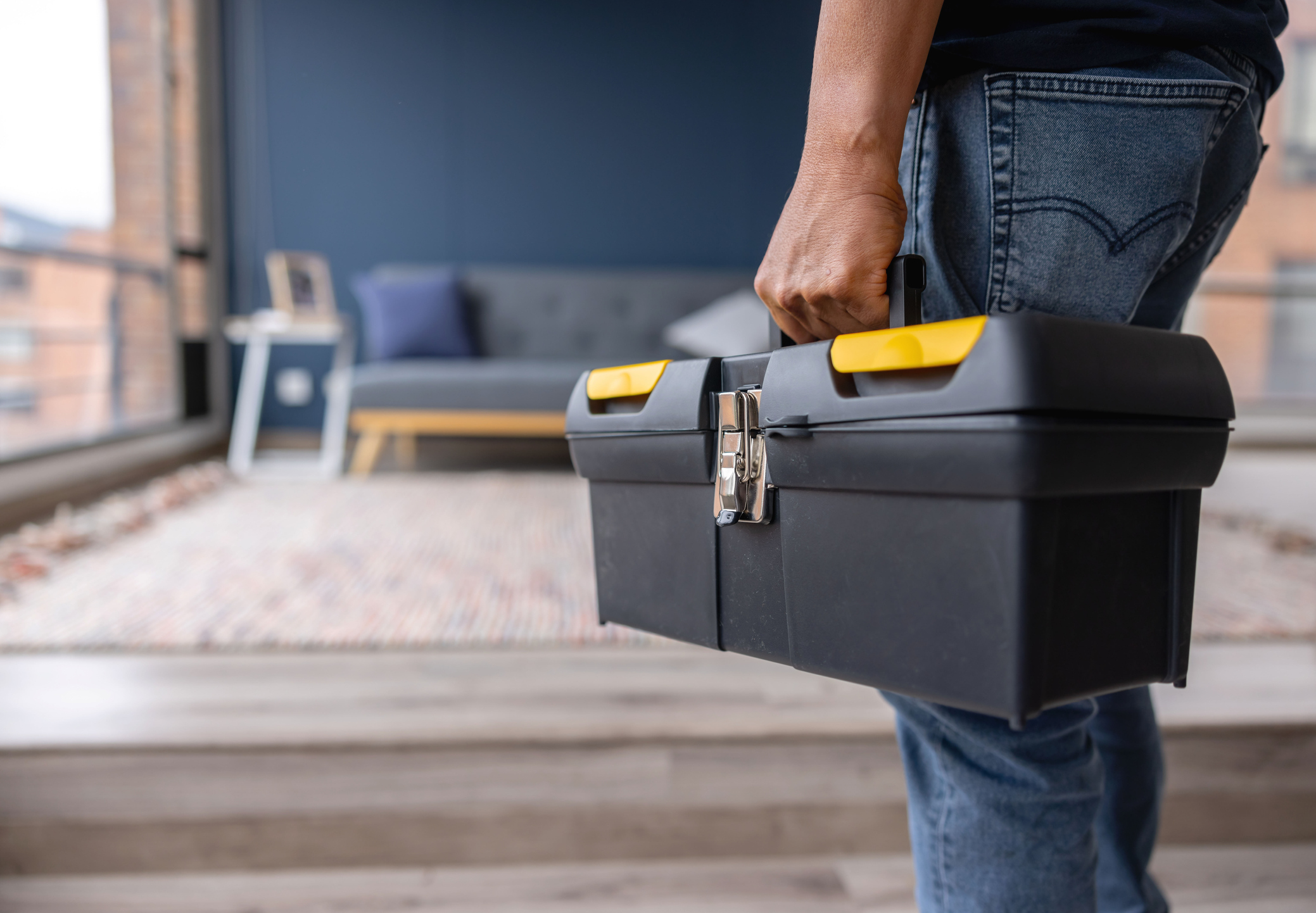 Close-up on an electrician carrying a toolbox while working at a house