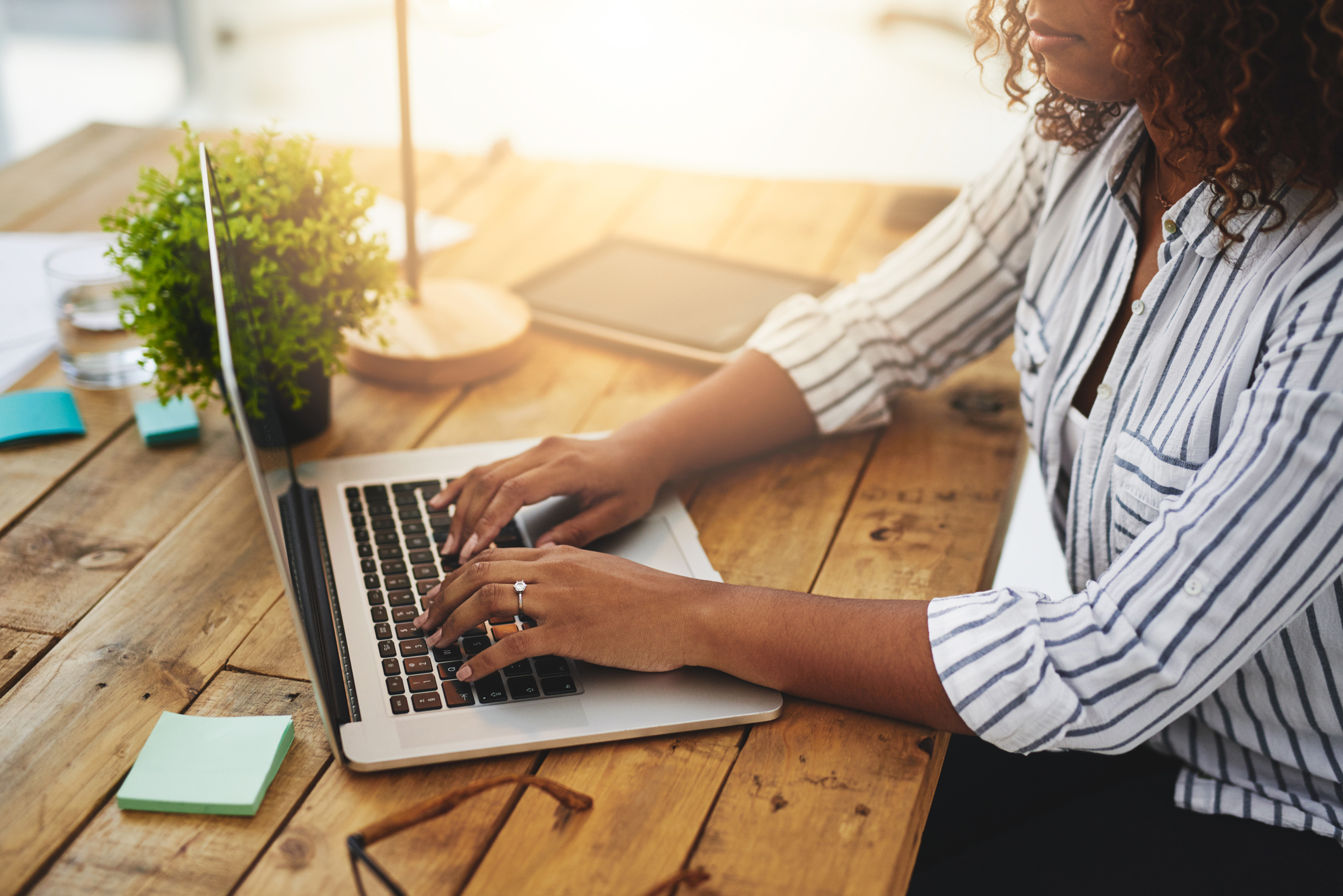 Cropped shot of a woman using her laptop on a wooden table