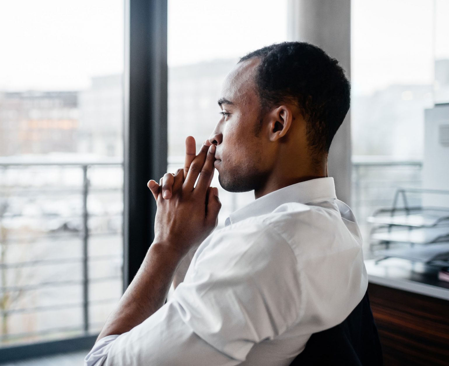 pensive black businessman looking out the window