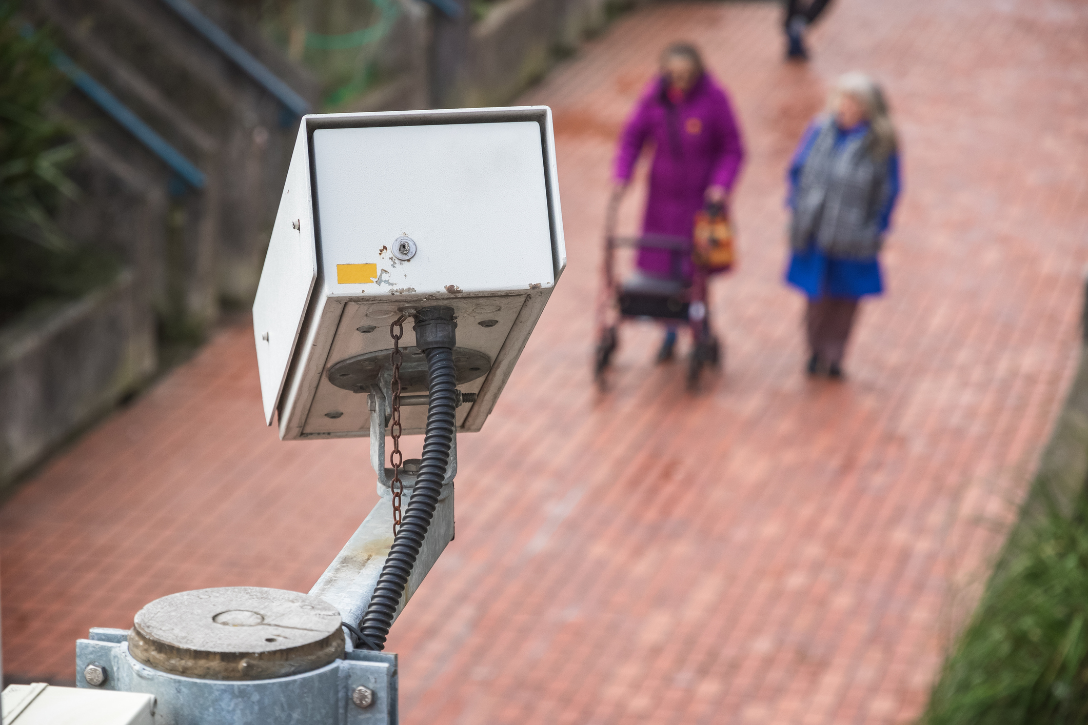 Surveillance camera with unidentified walking elderly people in the background