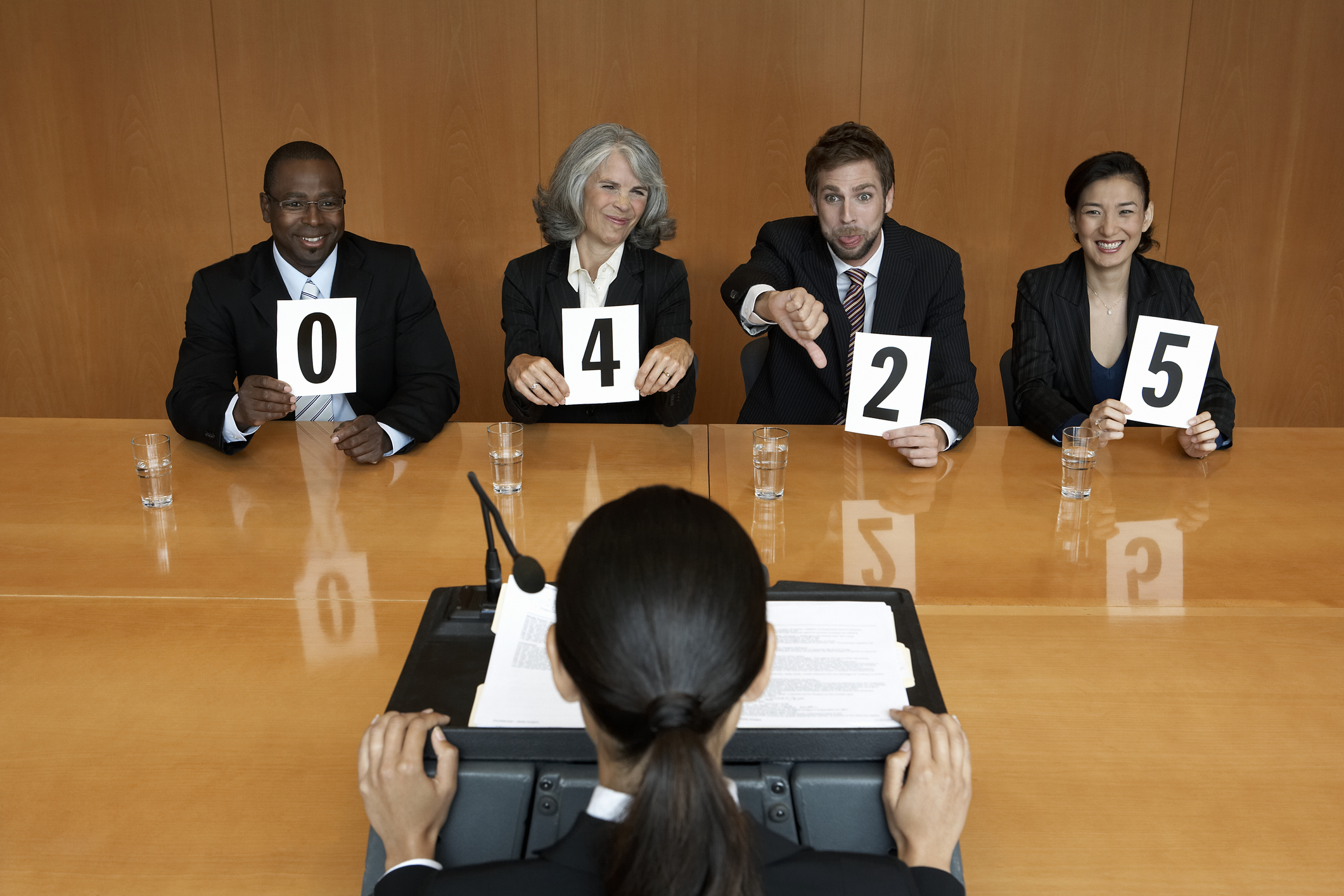 Businesswoman at interview, executives holding score cards, jeering