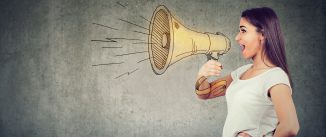 Young woman screaming into loudspeaker