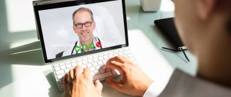 Businessman's hand videoconferencing with happy doctor on laptop
