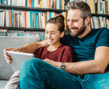 father and daughter having fun with digital tablet on couch