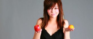 Woman holding an apple and an orange.