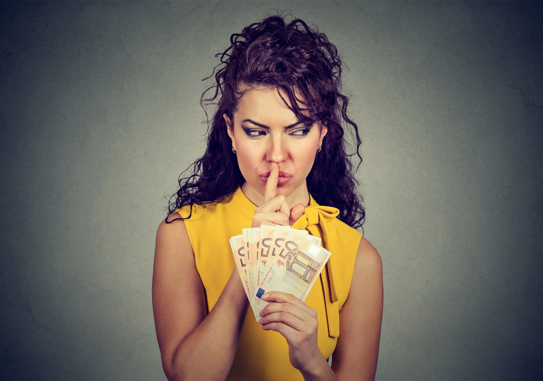 Woman holding pile of money and asking for silence.