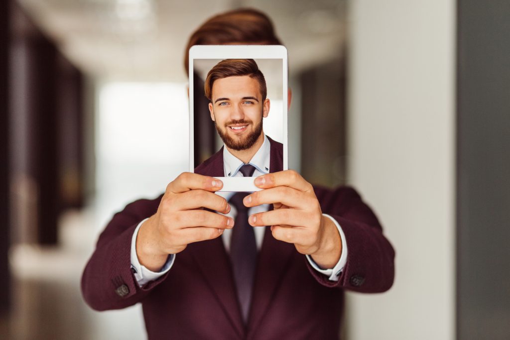 Smiling businessman showing photo on tablet