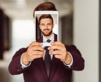Smiling businessman showing photo on tablet