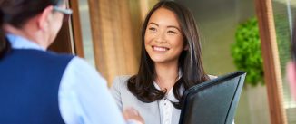 Young job candidate holding a portfolio and shaking hands with hiring manager.