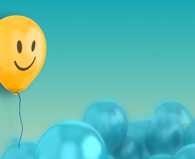 A large group of blue baloons with a yellow one with a smiley face on it floating above the rest