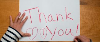 Child writes thank you on paper