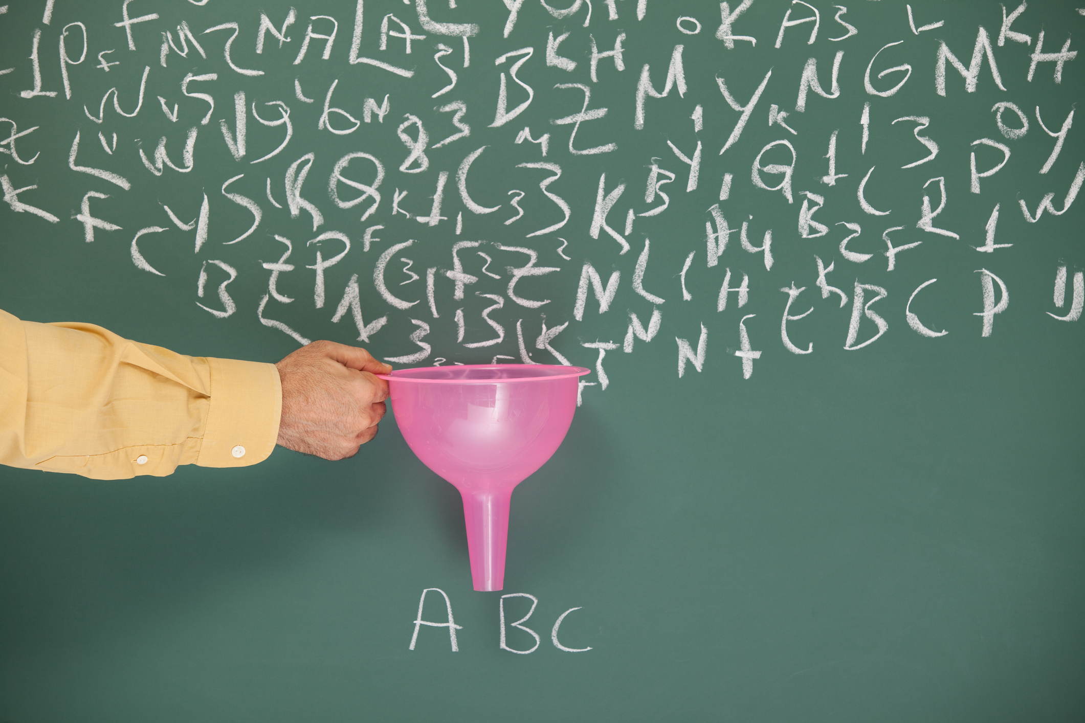 A funnel in hand of man filtering letters written on blackboard by chalk.Search engine optimization -SEO- concept is aimed.The hand is on the left side of the horizontal frame.The funnel pink color is for having attention on filtering. The letters "ABC" is written under the funnel.Taken with a full frame DSLR camera.