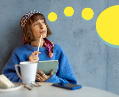 A woman sitting at a table with coffee and cake, with a yellow thought bubble coming from her head with a heart icon inside a series of rings.