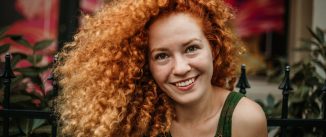 Young woman with red hair sitting outside.