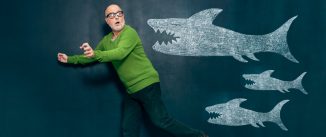 Man running away from three sharks drawn on a chalkboard