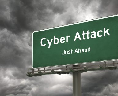 Green road sign saying Cyber Attack Just Ahead against grey cloudy background